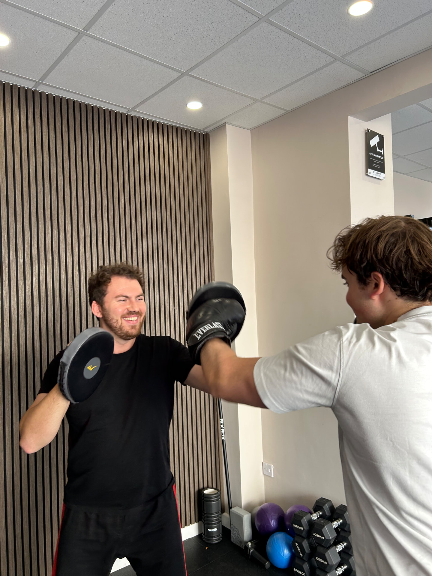 Archie Dunnett coaching a one-to-one martial arts session, holding focus pads as a student punches
